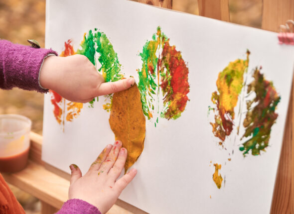 little girl artist paints autumn leaves in the park