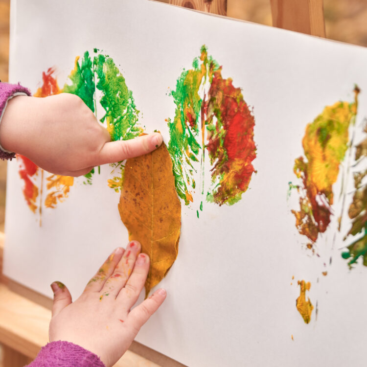 little girl artist paints autumn leaves in the park